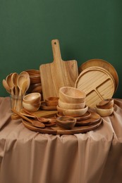 Set of wooden dishware and utensils on table against green background