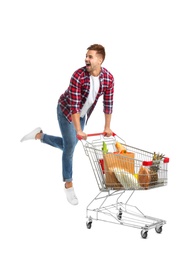 Young man with full shopping cart on white background