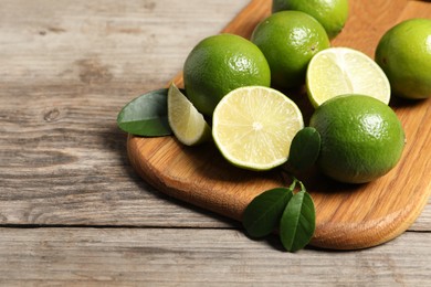 Photo of Fresh ripe limes on wooden table, closeup. Space for text