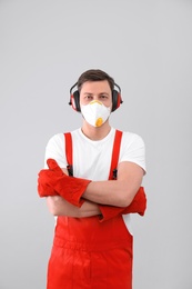 Photo of Male industrial worker in uniform on light background. Safety equipment