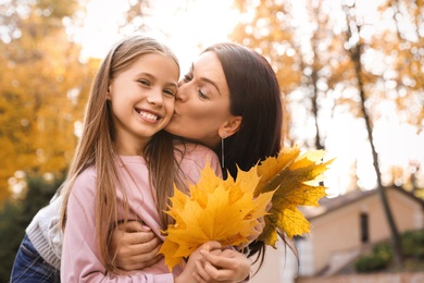 Photo of Happy mother and daughter with yellow leaves in park. Autumn walk