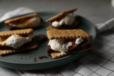 Photo of Delicious marshmallow sandwiches with crackers and chocolate on plate, closeup