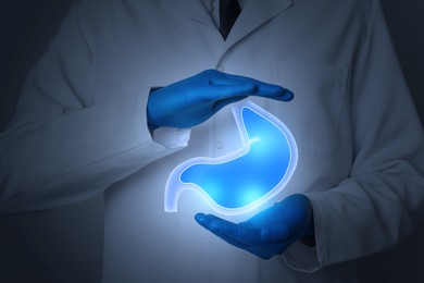Image of Symptoms and treatment of heartburn and other gastrointestinal diseases. Doctor holding stomach illustration on dark background, closeup
