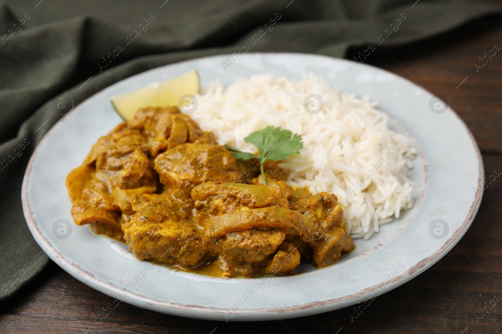 Photo of Delicious chicken curry with rice on wooden table, closeup