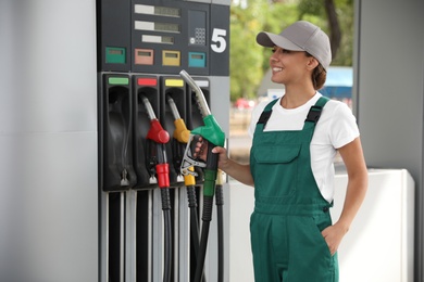 Photo of Young worker with fuel pump nozzle at modern gas station