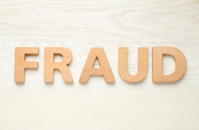 Photo of Word Fraud made of wooden letters on white background, flat lay