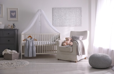 Photo of Baby room interior with comfortable crib and armchair