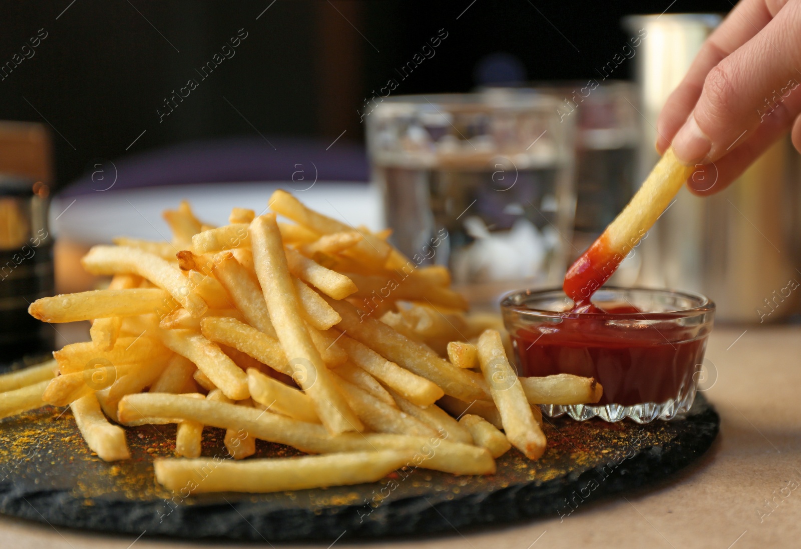 Photo of Woman dipping French fries into red sauce in cafe, closeup