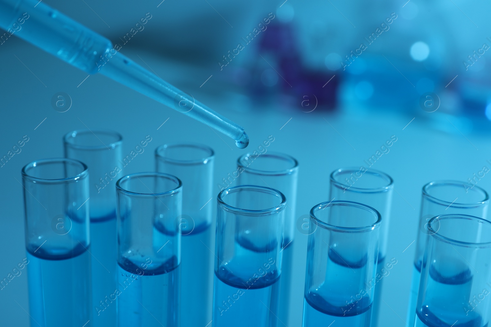 Photo of Dripping reagent into test tube with blue liquid, closeup. Laboratory analysis