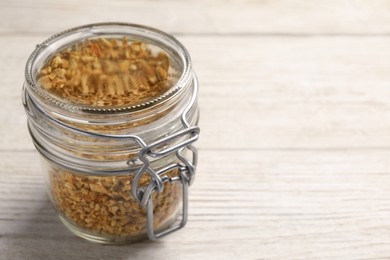 Photo of Jar of dried orange zest seasoning on white wooden table. Space for text