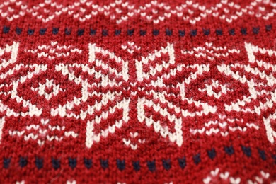 Photo of Warm Christmas sweater with snowflakes as background, closeup