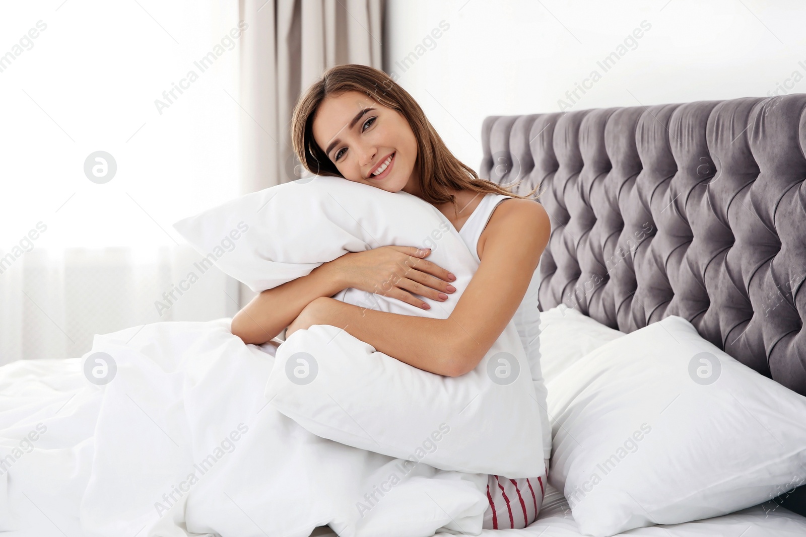 Photo of Beautiful teen girl hugging comfortable pillow in bed at home