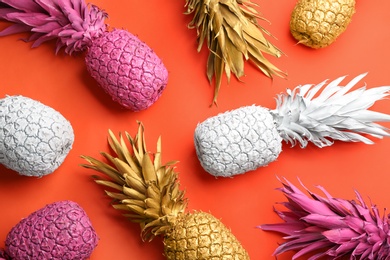 Many colorful pineapples on orange background, flat lay. Creative concept
