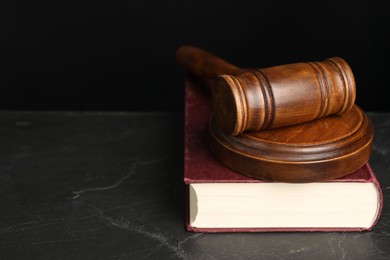 Photo of Wooden gavel, sound block and book on dark textured table, closeup. Space for text