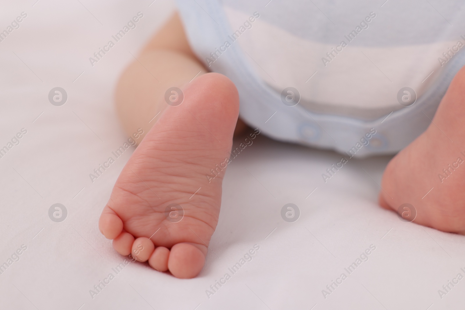 Photo of Newborn baby lying on white blanket, closeup