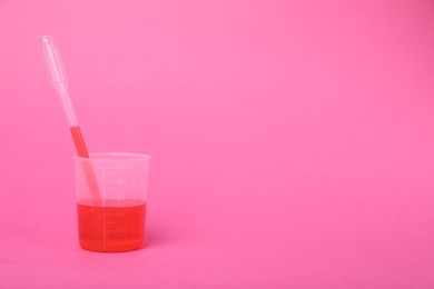 Photo of Beaker with liquid and stirring rod on bright pink background, space for text. Kids chemical experiment toy
