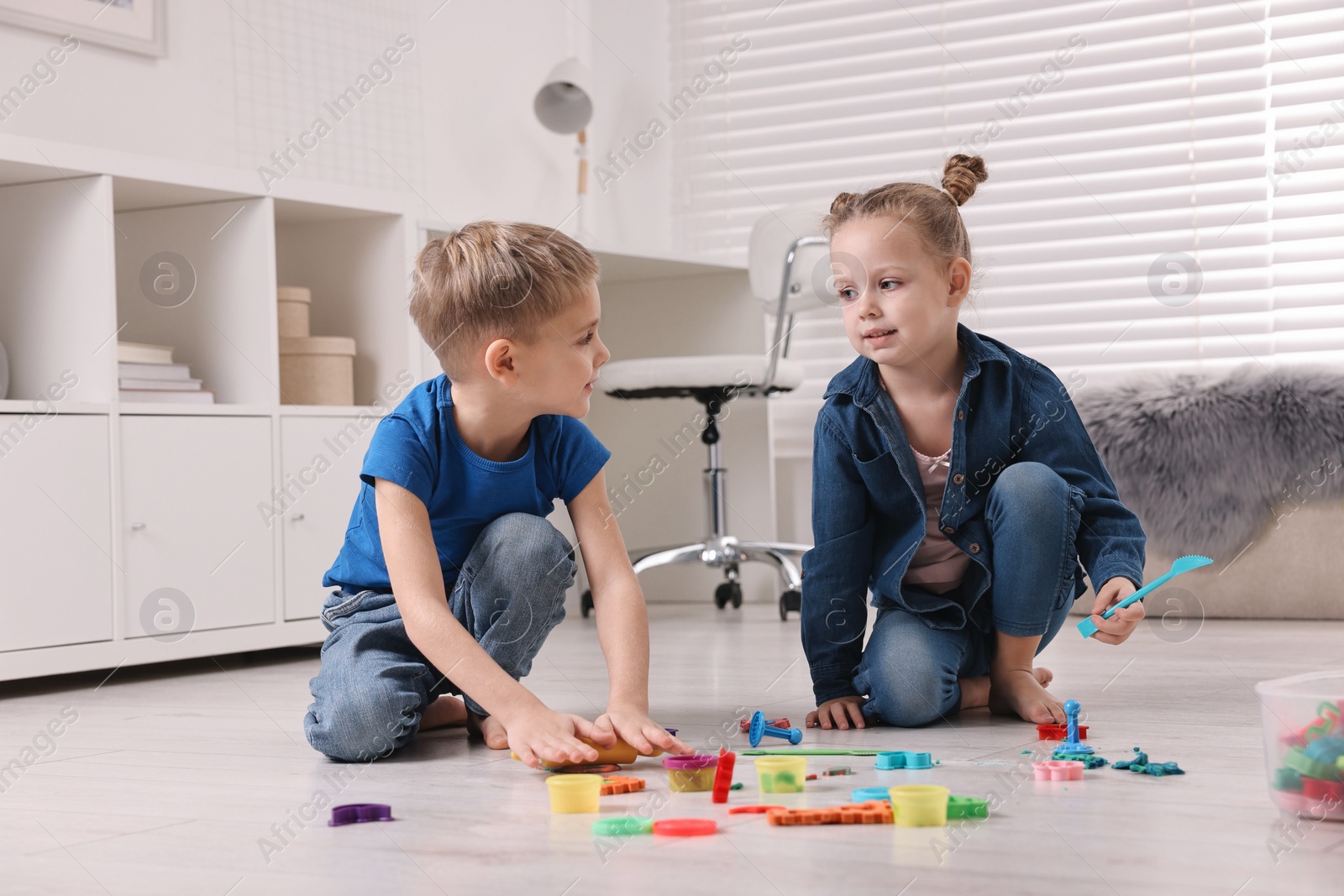 Photo of Cute little children playing on warm floor at home. Heating system