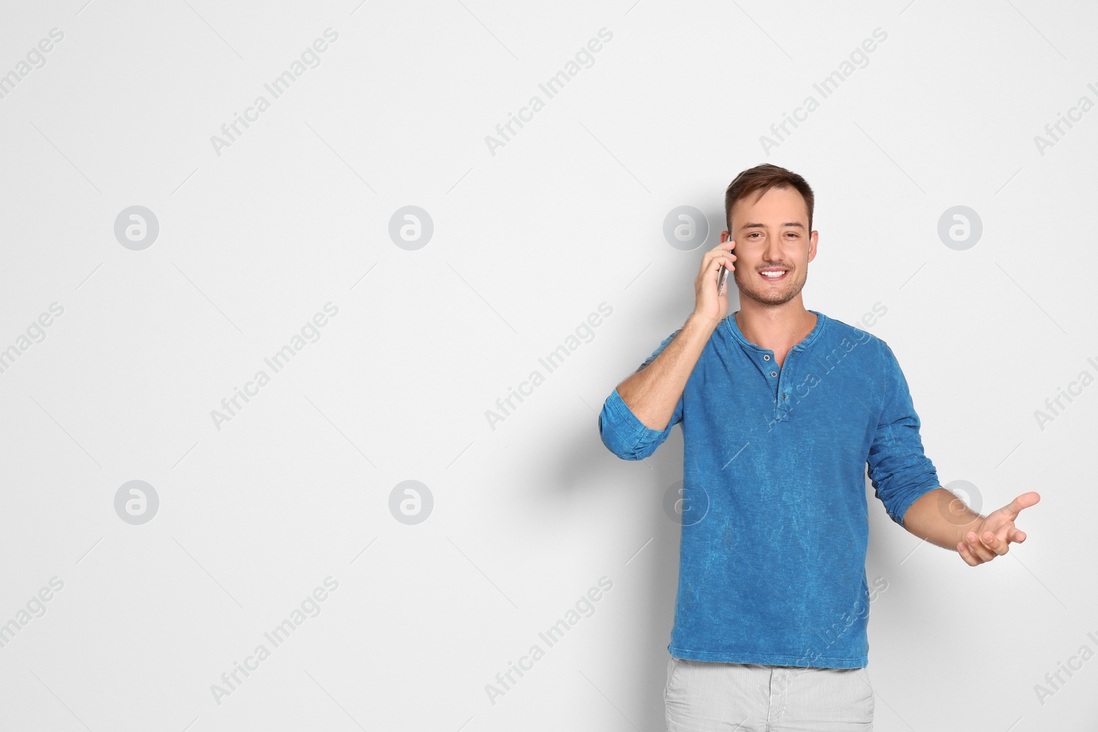 Photo of Young man talking on phone against white background. Space for text