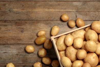 Photo of Raw fresh organic potatoes on wooden background, top view. Space for text