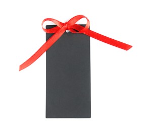 Photo of Blank black gift tag with red satin ribbon on white background, top view. Space for design