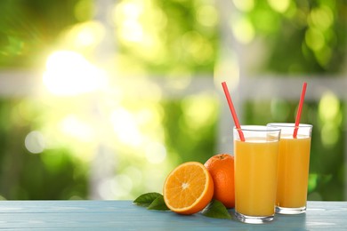 Image of Fresh orange juice on light blue wooden table against blurred background. Space for text