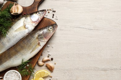 Fresh raw pike perches and ingredients on light wooden table, flat lay with space for text. River fish