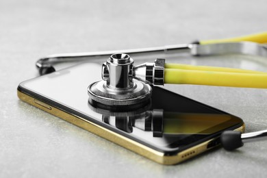 Photo of Stethoscope and modern smartphone on grey table