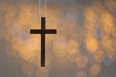 Wooden cross against blurred lights, closeup with space for text. Religion of Christianity