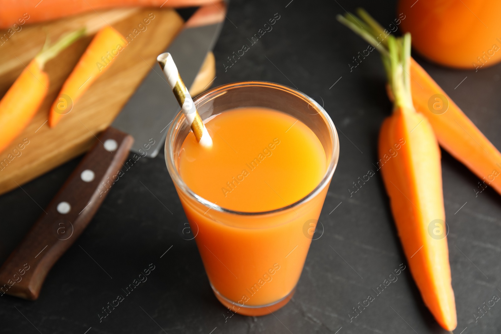 Photo of Glass of freshly made carrot juice on black table, closeup