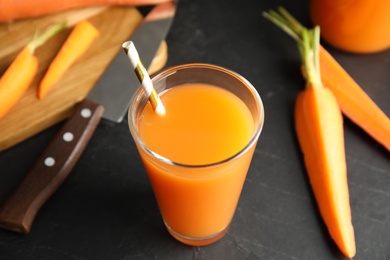 Photo of Glass of freshly made carrot juice on black table, closeup