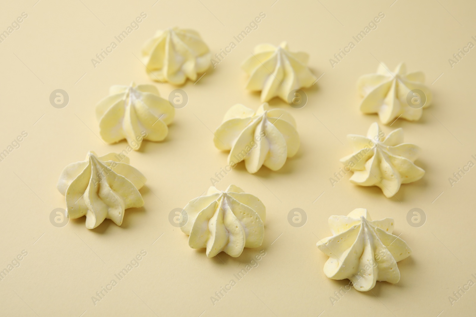 Photo of Delicious meringue cookies on beige background, closeup