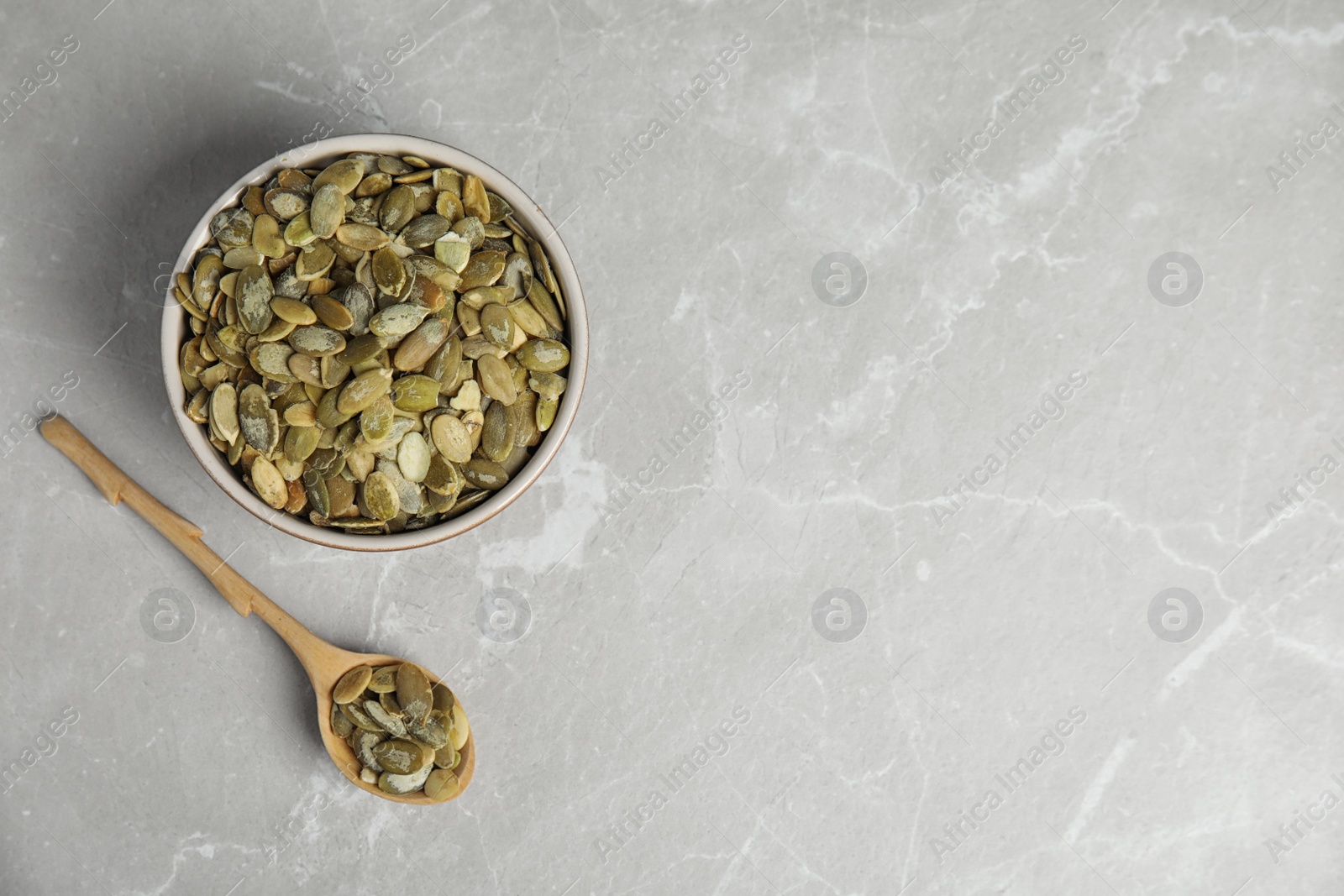 Photo of Raw pumpkin seeds on light grey marble table, flat lay. Space for text