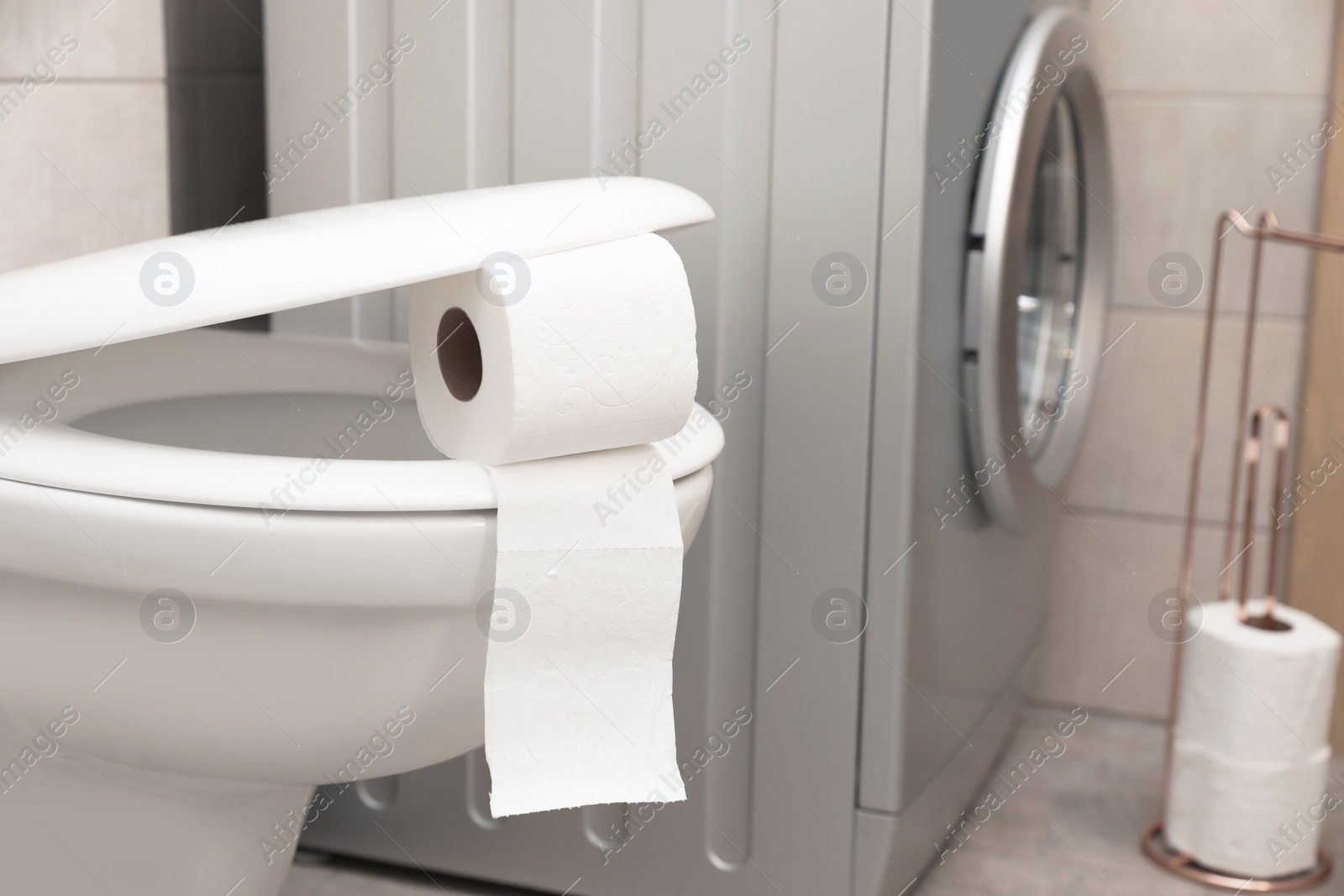 Photo of Toilet bowl with paper roll in bathroom