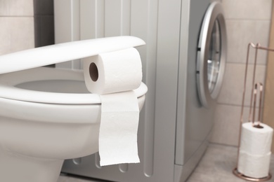 Photo of Toilet bowl with paper roll in bathroom