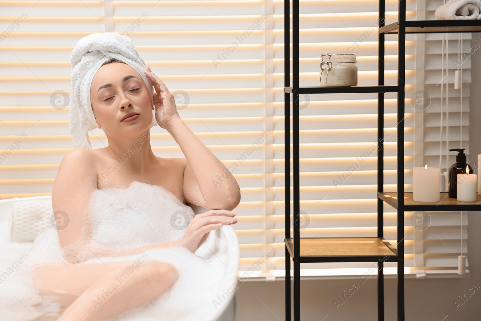 Photo of Beautiful woman taking bath with foam in tub indoors