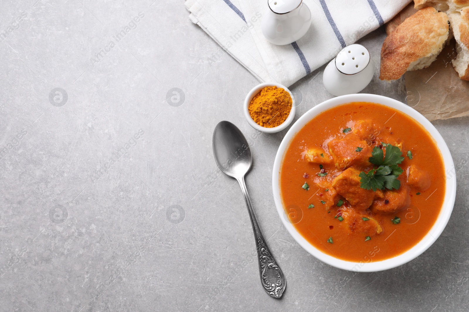 Photo of Bowl of delicious chicken curry on light grey table, flat lay. Space for text