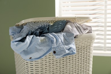 Plastic laundry basket with clothes indoors, closeup