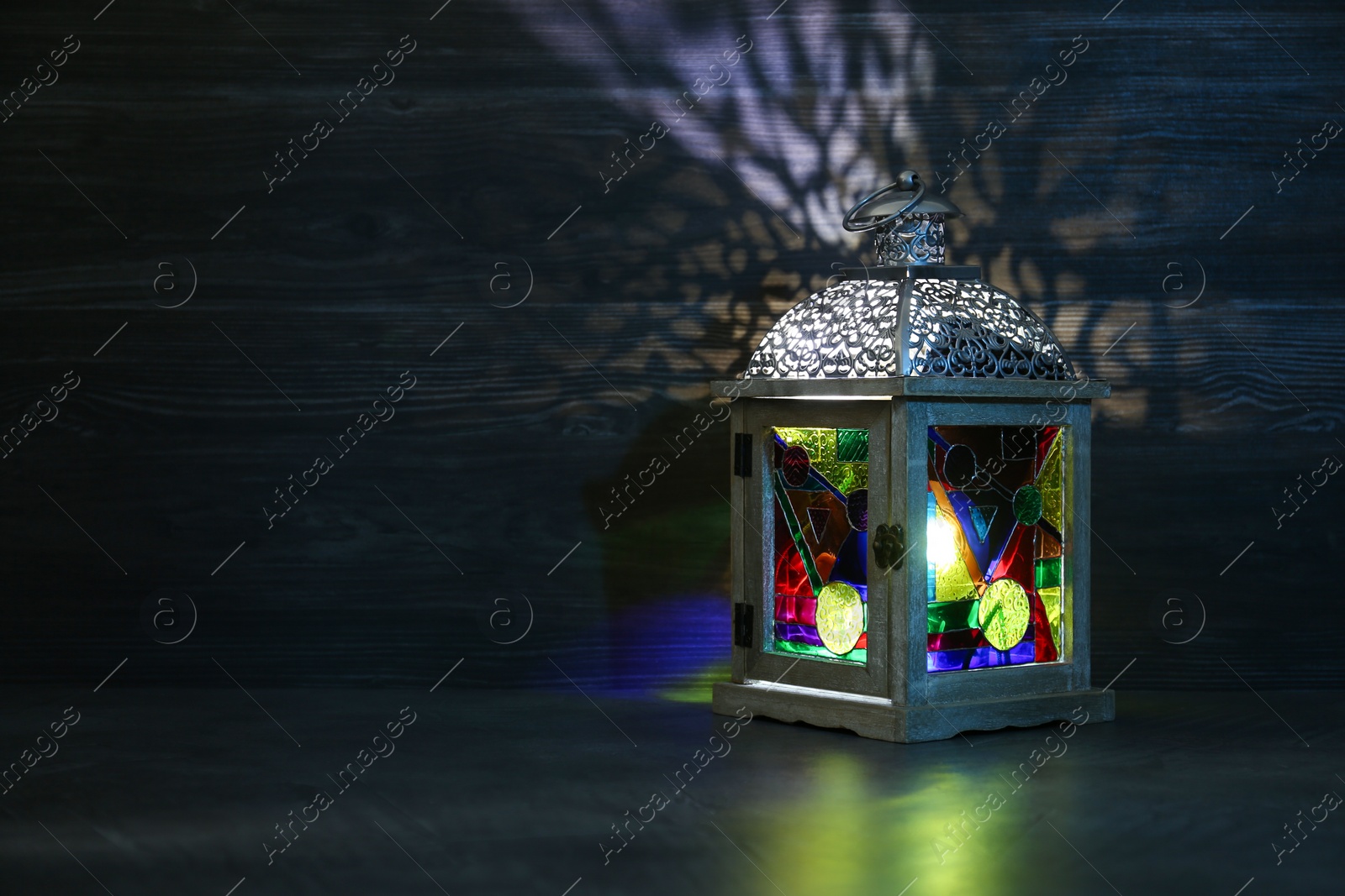 Photo of Decorative Arabic lantern on table against dark background. Space for text