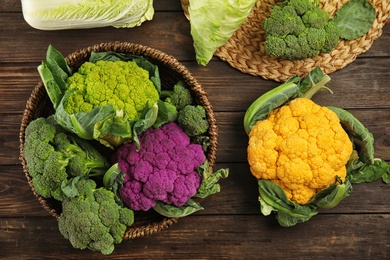 Photo of Different cabbages on wooden table, top view. Healthy food