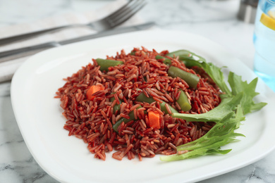 Photo of Tasty brown rice with vegetables on white marble table