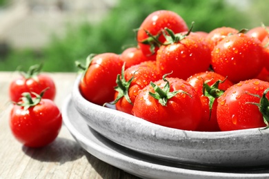 Photo of Plates with fresh ripe tomatoes on table outdoors