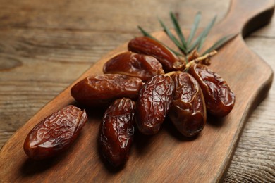 Photo of Branch of sweet dried dates on wooden table, closeup