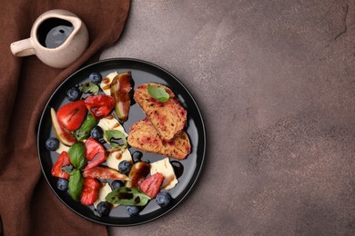 Photo of Delicious salad with brie cheese, berries and balsamic vinegar on brown table, flat lay. Space for text