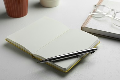 Photo of Notebooks and pen on white table, closeup