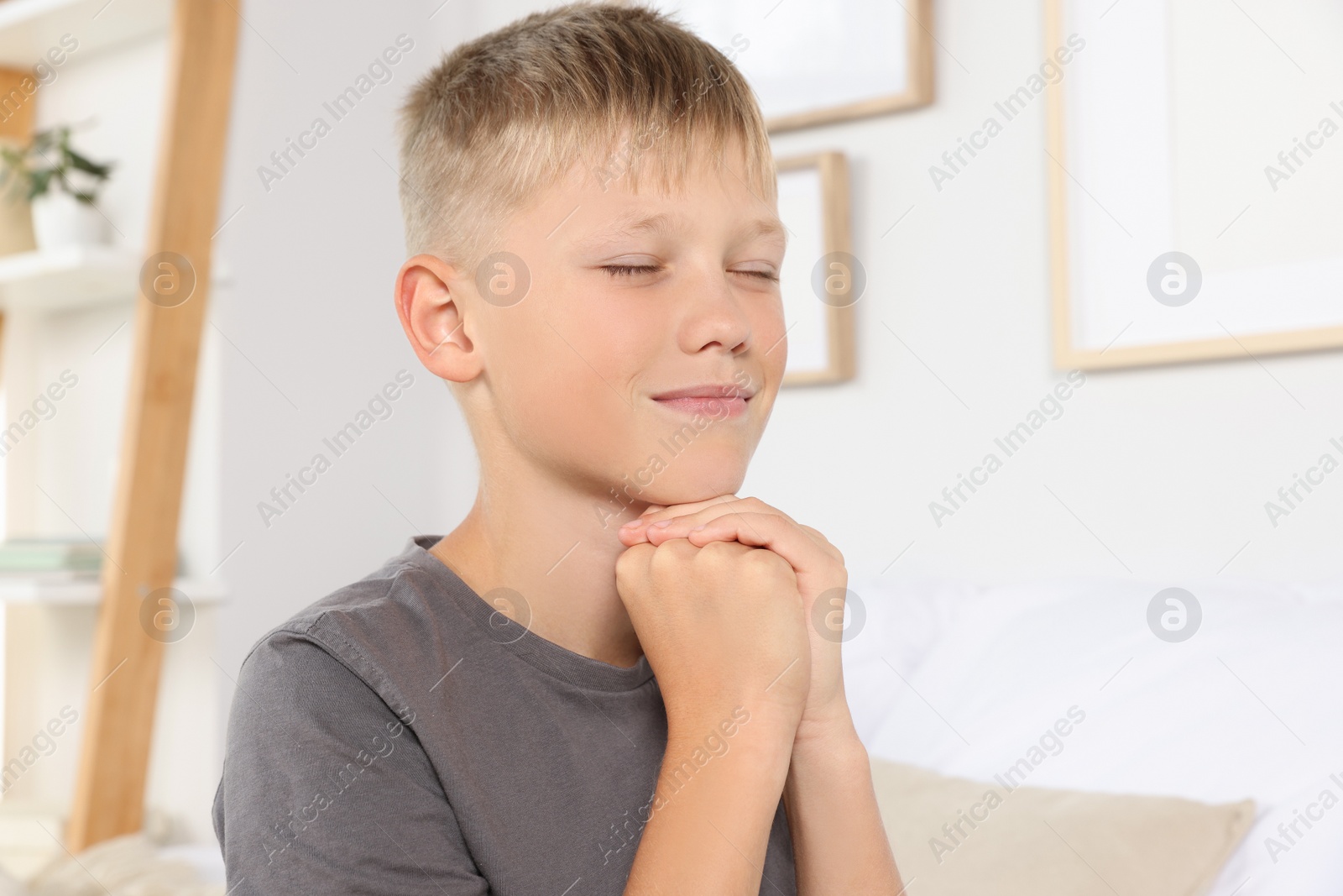 Photo of Boy with clasped hands praying at home