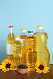 Photo of Bottles of cooking oil, sunflowers and seeds on wooden table