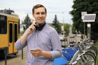 Photo of Handsome young man with headphones and smartphone on city street