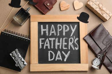 Photo of Chalkboard with phrase HAPPY FATHER'S DAY and male accessories on beige background