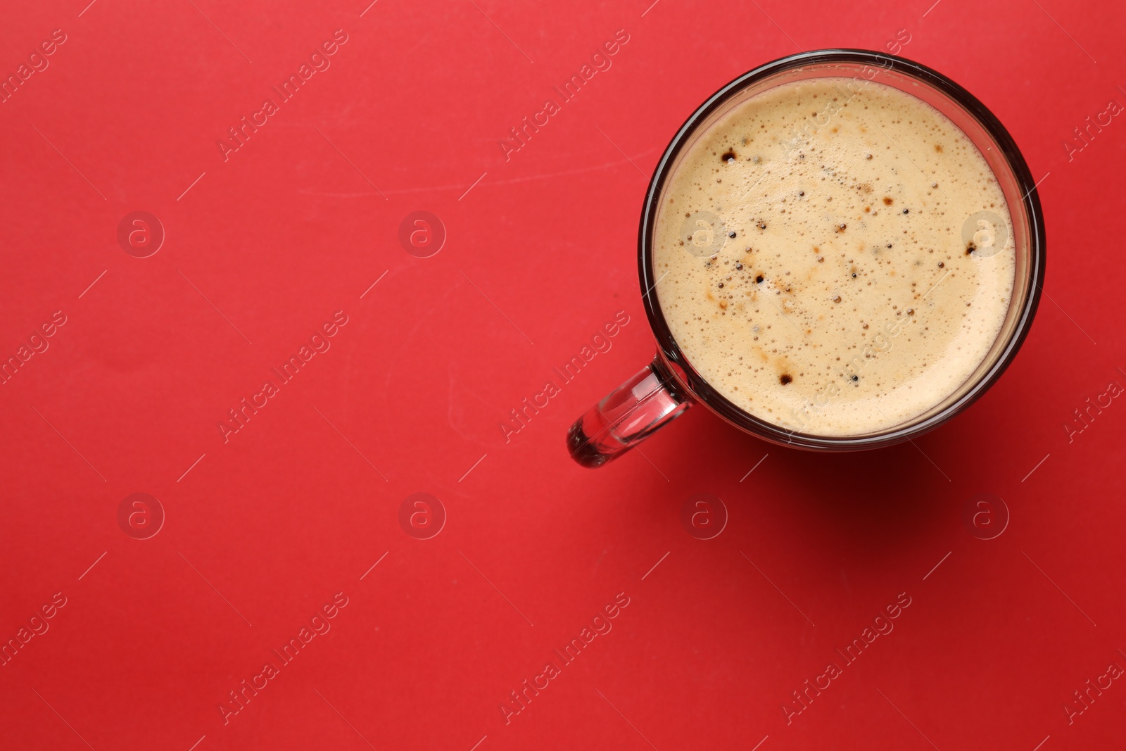 Photo of Fresh coffee in cup on red background, top view. Space for text