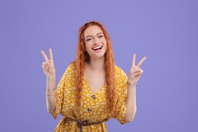 Photo of Beautiful young hippie woman showing V-sign on violet background